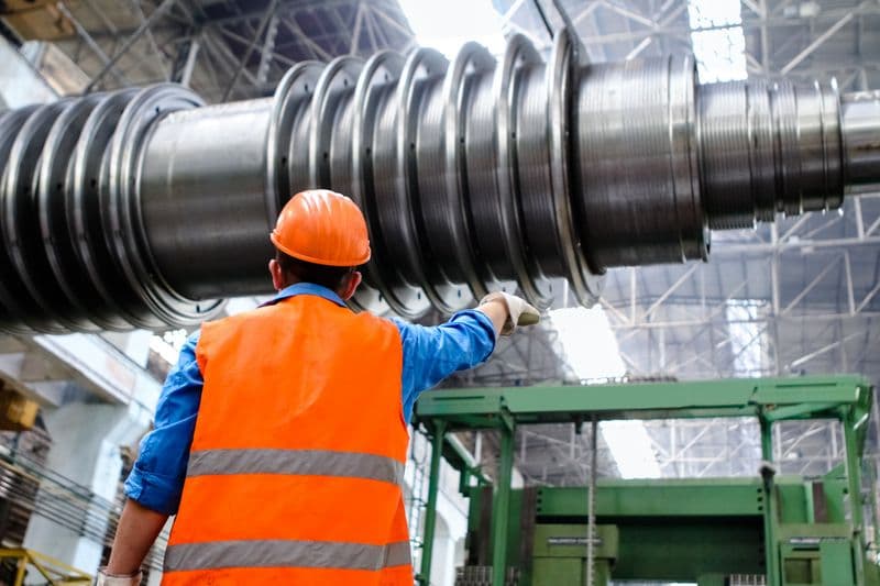 Worker in a hard hat and hi-vis vest beside heavy machinery