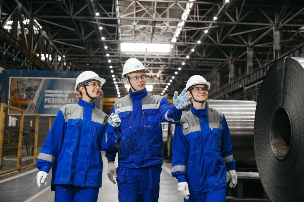 Plant workers in hard hats walking a steel mill floor